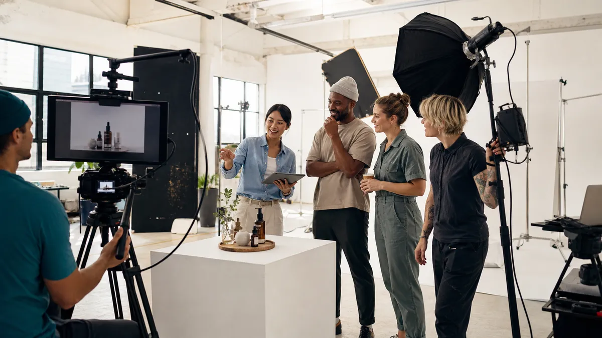 Small business owner reviewing a product video shoot with a diverse professional film crew in a bright studio